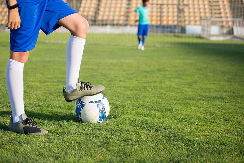 a person stepping on the ball while wearing cleats